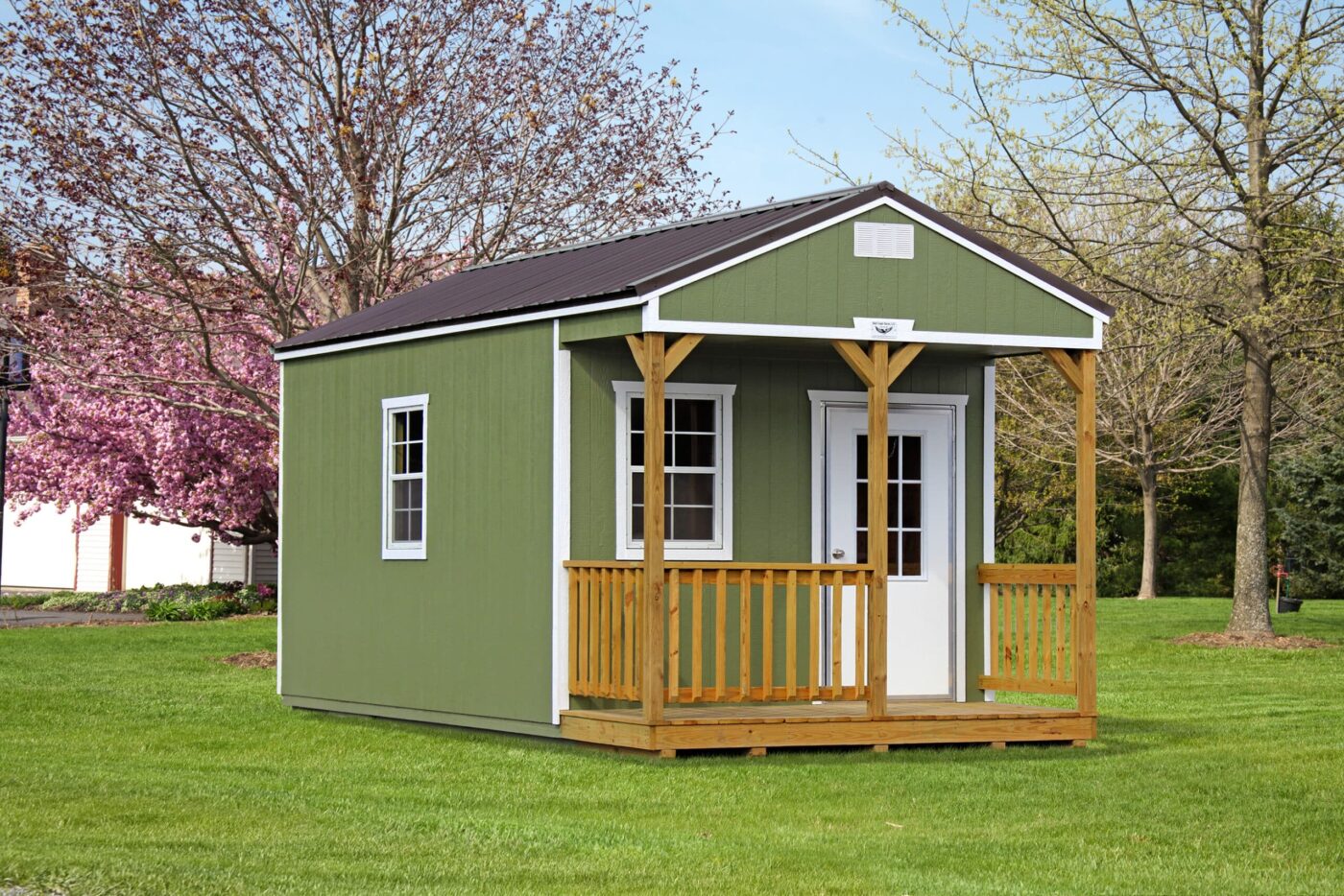 a light green portable cabin shed with white trim, a dark grey metal roof, a white door, and a wood porch for sale in bradford AR